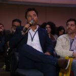 Marcos Barral participa do Painel de Debates durante o Seminário de Alvenaria Estrutural, segurando microfone e interagindo com o público no auditório.