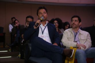 Marcos Barral participa do Painel de Debates durante o Seminário de Alvenaria Estrutural, segurando microfone e interagindo com o público no auditório.