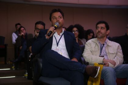 Marcos Barral participa do Painel de Debates durante o Seminário de Alvenaria Estrutural, segurando microfone e interagindo com o público no auditório.