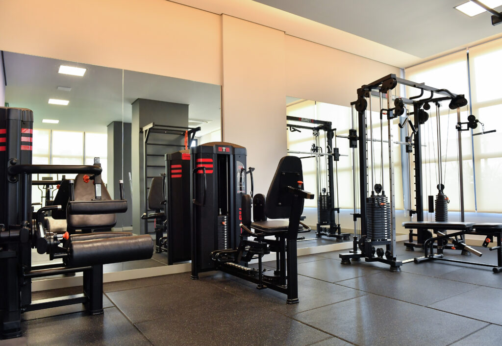 Academia moderna com equipamentos de musculação, espelhos amplos e iluminação natural, projetada para proporcionar conforto, funcionalidade e bem-estar em empreendimentos residenciais.